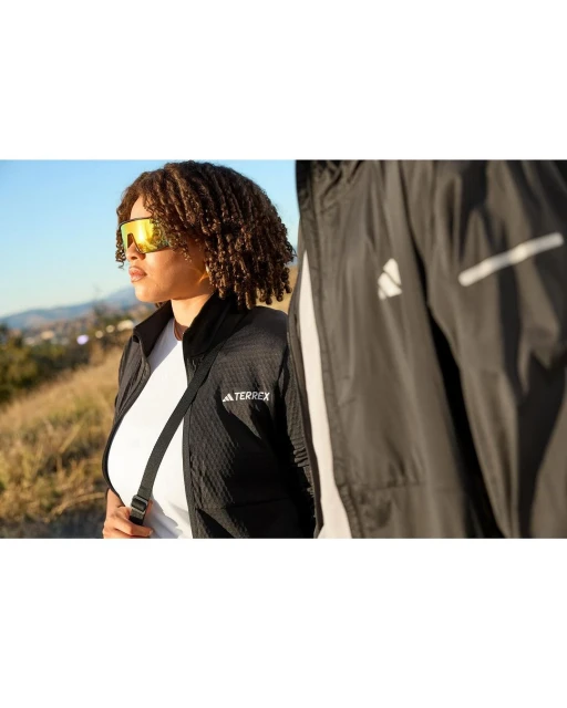 Two people wearing Adidas Terrex athletic jackets outdoors on a sunny day; one in the foreground and a second person partially visible.