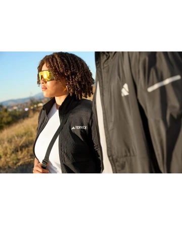 Two people wearing Adidas Terrex athletic jackets outdoors on a sunny day; one in the foreground and a second person partially visible.