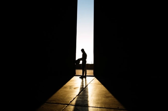 Silhouette of a racing driver standing in a dark doorway with bright light streaming through