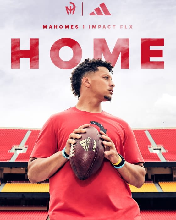 Football player Patrick Mahomes holding a football, posing in a red tee shirt in a stadium with a Mahomes logo and Adidas logo.