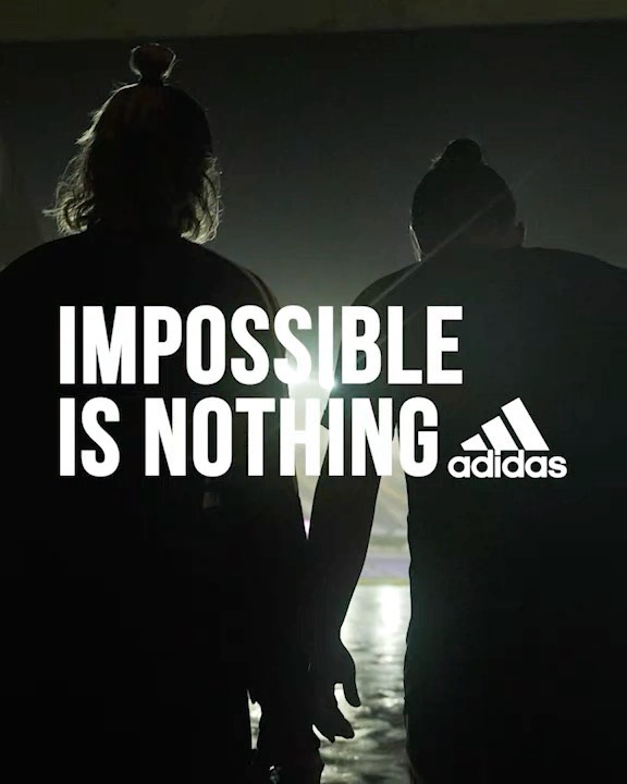 Silhouette of two people and the Adidas logo with tagline 'Impossible is Nothing', captured with dark, moody lighting.