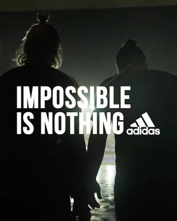 Silhouette of two people and the Adidas logo with tagline 'Impossible is Nothing', captured with dark, moody lighting.