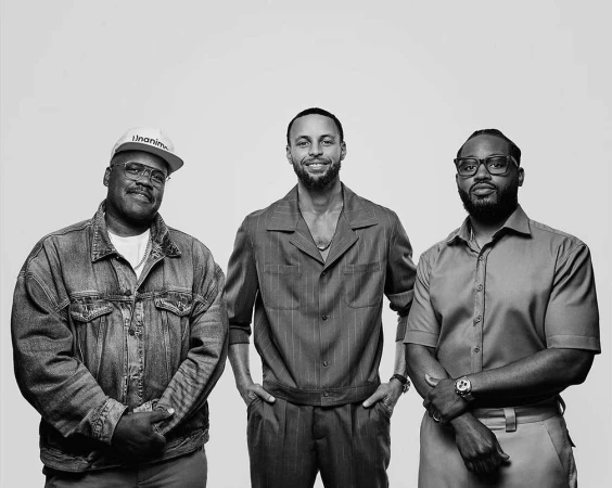 Black and white portrait of three men posing together against a plain light background photographed by Ryan Young.