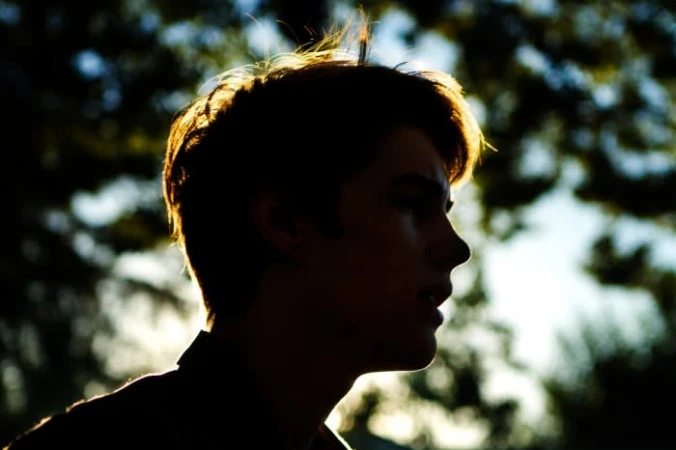 Profile silhouette of a young man against a backlit outdoor foliage background by photographer Ryan Young