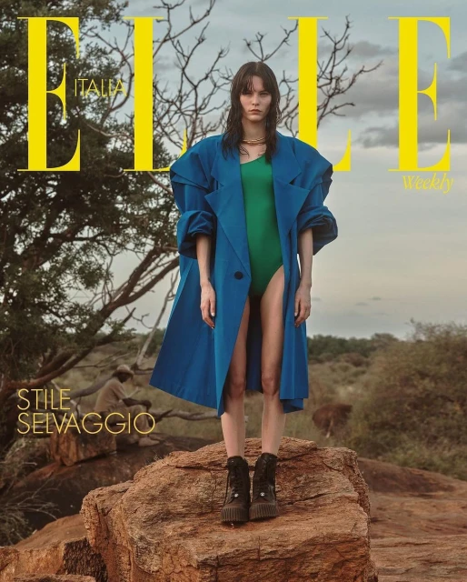 Elle Italia cover features a female model in a teal coat and green bodysuit standing on a rocky surface, with a savanna backdrop.
