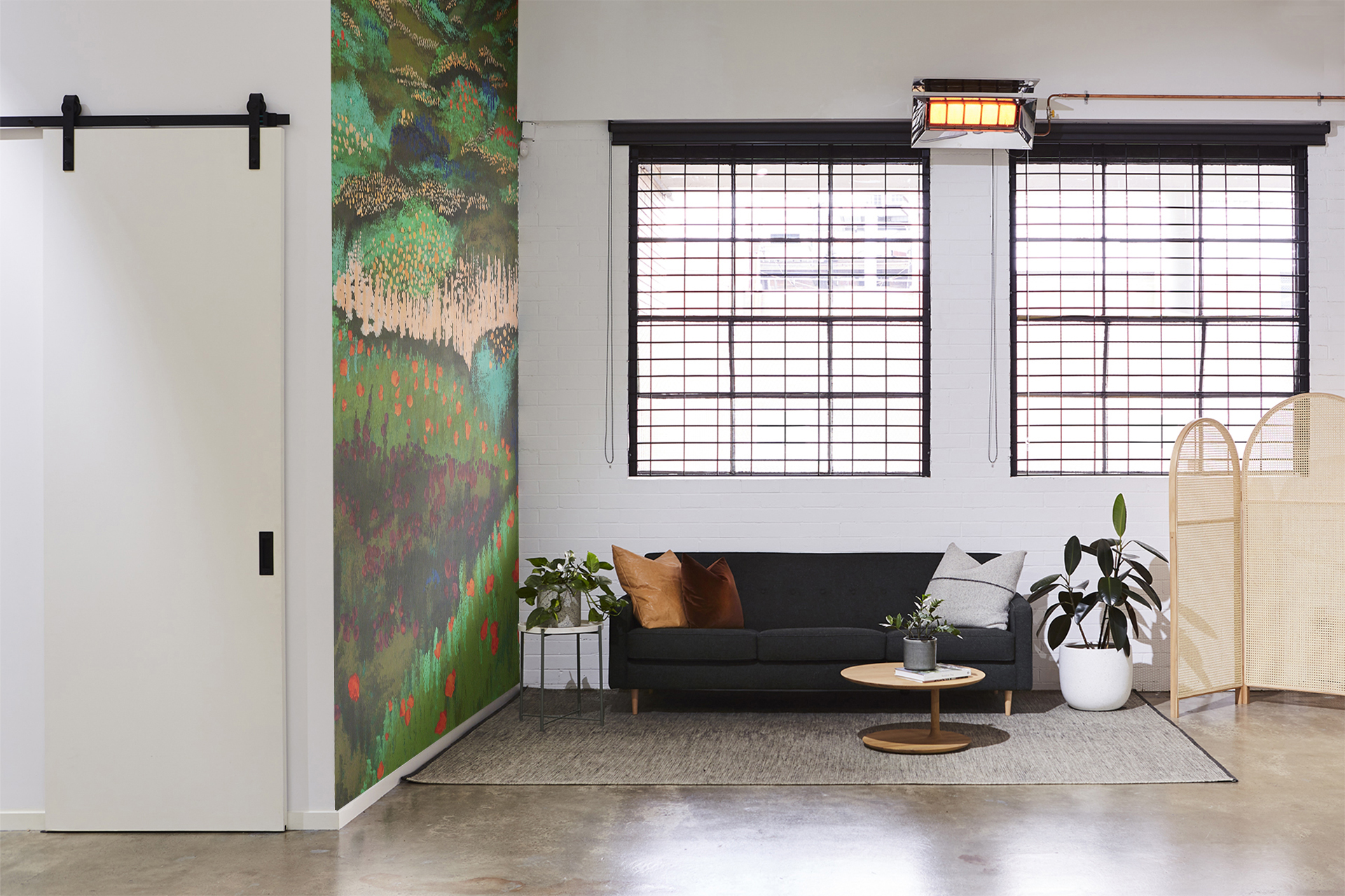 Modern interior showcases a gray sofa with cushions, plants, two large windows, and an abstract painting on the wall.
