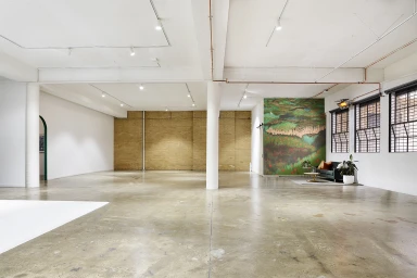 Spacious industrial photo studio in Melbourne featuring exposed brick walls, polished concrete floors, and large multi-pane windows.