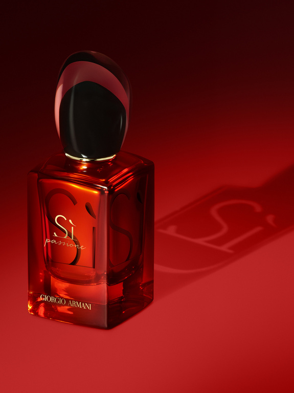 Giorgio Armani Si Passione perfume bottle against a red background. The fragrance bottle has a black cap and red glass. 