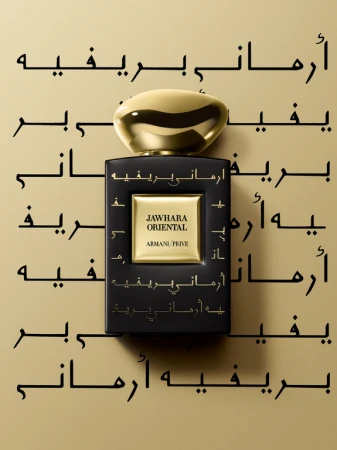 Close-up studio shot of a black Armani Prive fragrance bottle with a gold cap, featuring Arabic text and minimal lighting. 