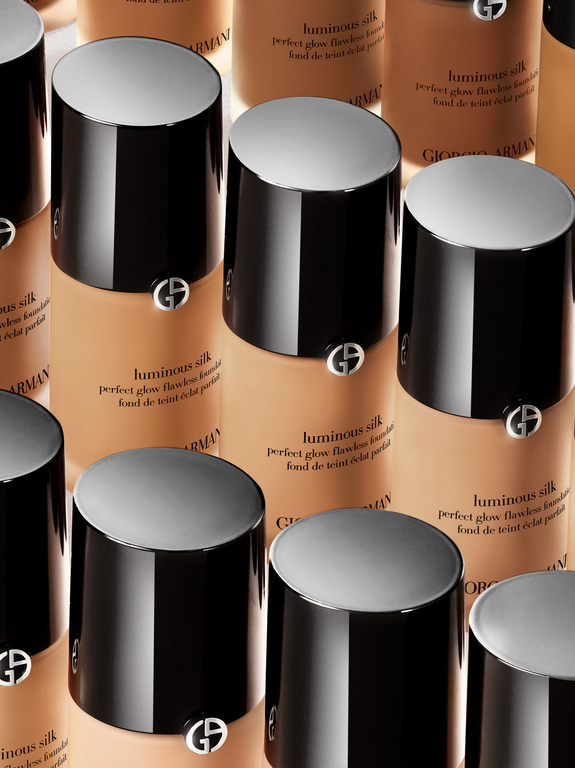 Close-up of multiple Giorgio Armani Luminous Silk foundation bottles featuring a black cap with the brand's logo, arranged in a grid.