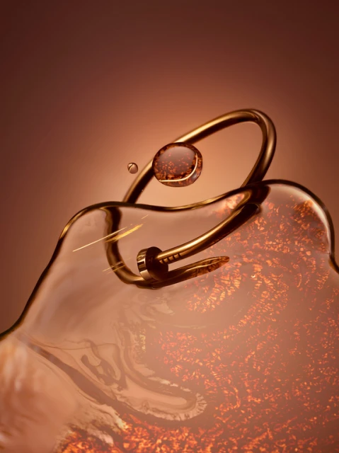 Close-up still life of a gold nail bracelet on a surface of liquid, with water droplets, against a gradient brown background.