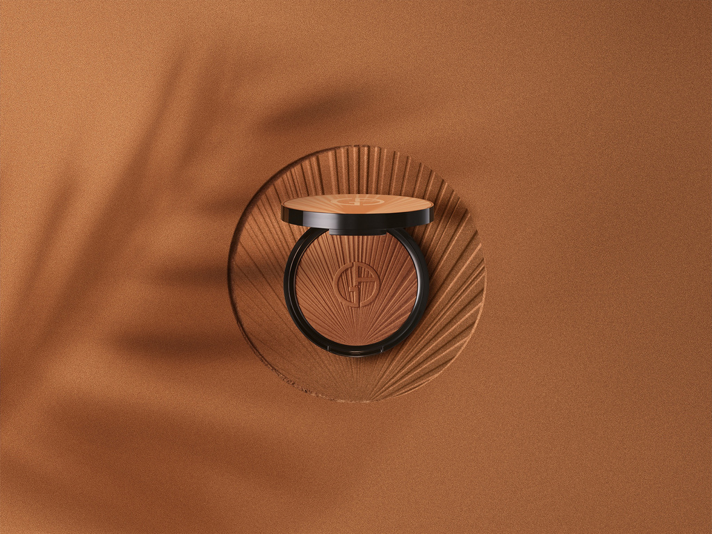 Close-up of bronze face powder on a textured platform against a bronze background with soft lighting and shadow patterns.