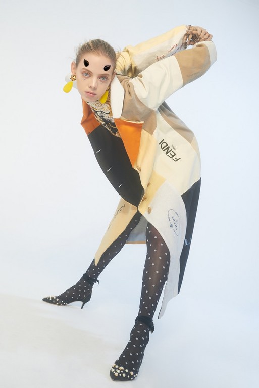 Fashionable woman poses in a patterned coat and polka-dot tights against a white backdrop, highlighting style and design.