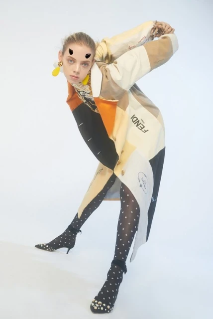 Fashionable woman poses in a patterned coat and polka-dot tights against a white backdrop, highlighting style and design.