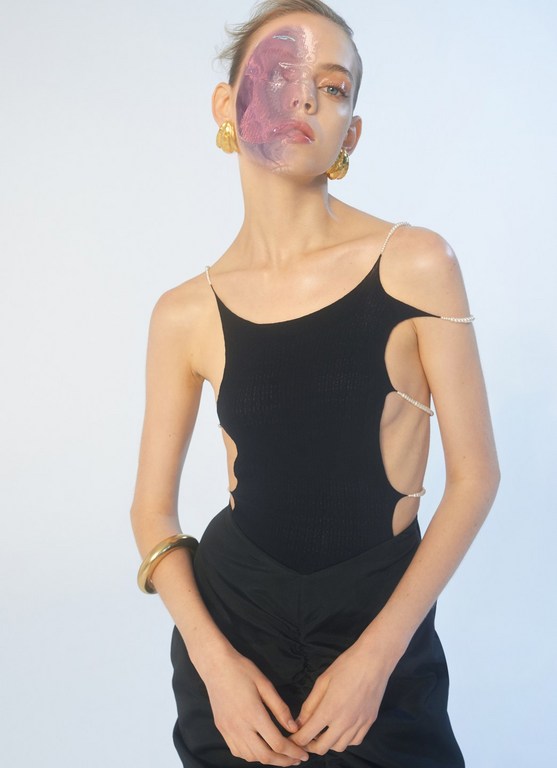 A striking studio shot of a woman wearing a black top and skirt, adorned with pearl straps, enhanced by a vibrant purple facial overlay.