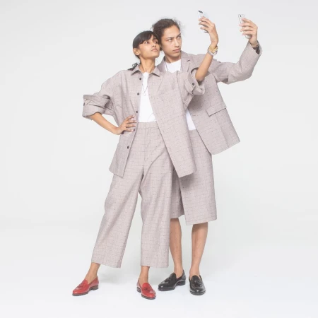 Two models wearing matching grey plaid co-ords taking a selfie with smartphones against a seamless white background.