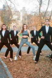 Five models posing outdoors in an autumn park with fallen leaves, featuring one in a matching patterned activewear set.
