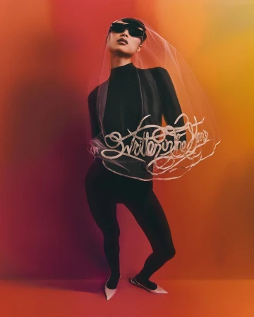 Model in black turtleneck, leggings, sunglasses, and a veil with script poses against an orange and red gradient backdrop.