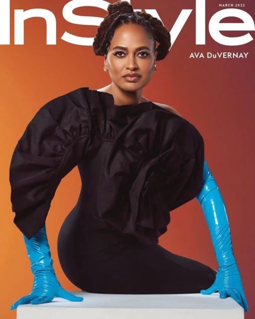 Ava DuVernay on InStyle magazine cover, March 2022. She wears a black dress with a large ruffled sleeve and turquoise opera gloves.