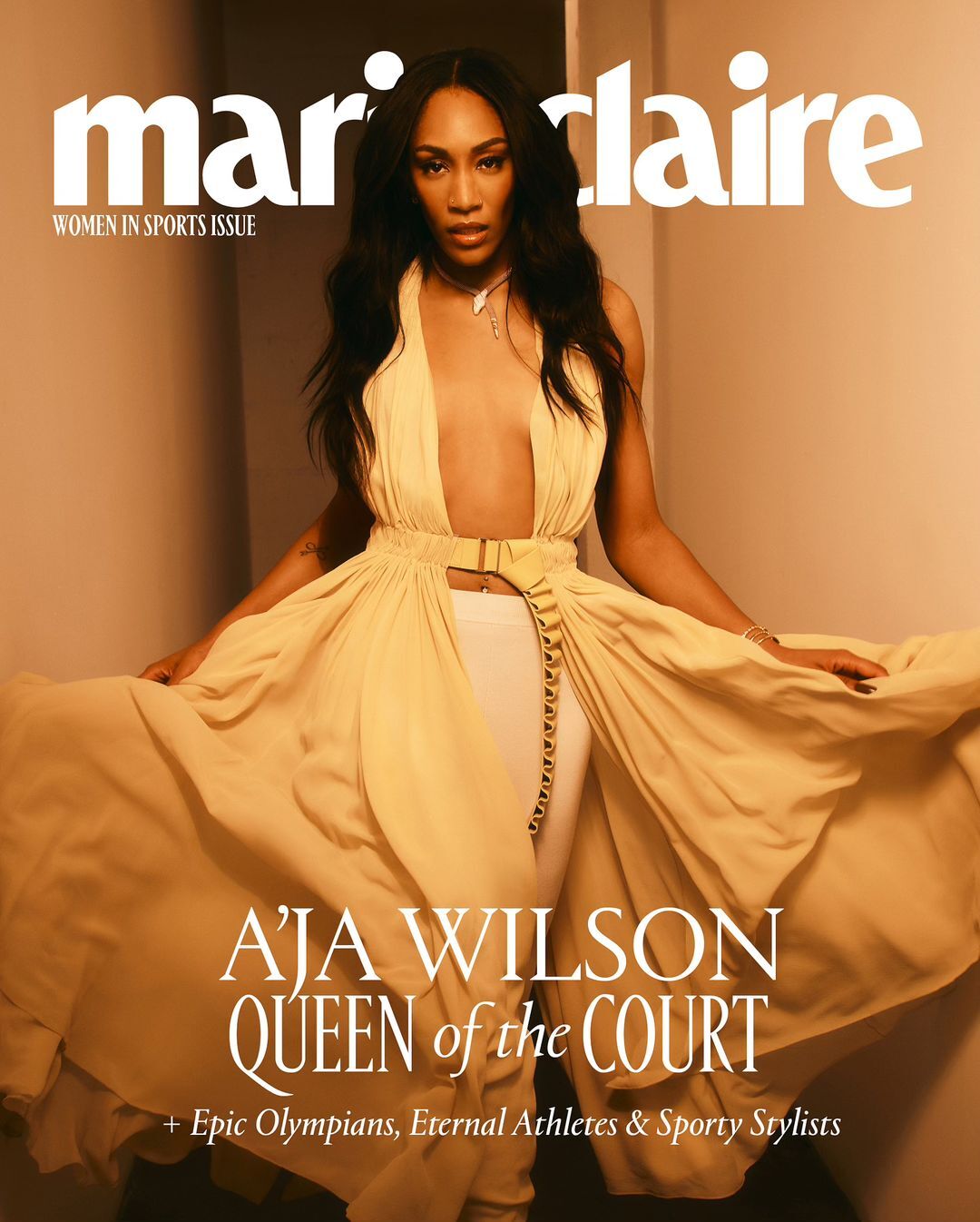Aja Wilson on the cover of Marie Claire's Women In Sports issue, wearing a flowing dress with white pants, in a studio setting.
