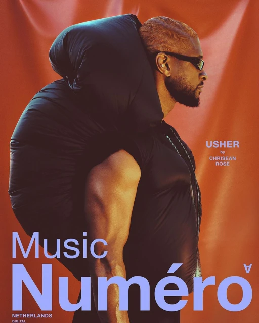 Singer Usher is on a magazine cover in orange tones, wearing black glasses and a sleeveless top, and carrying a puffy black wrap.