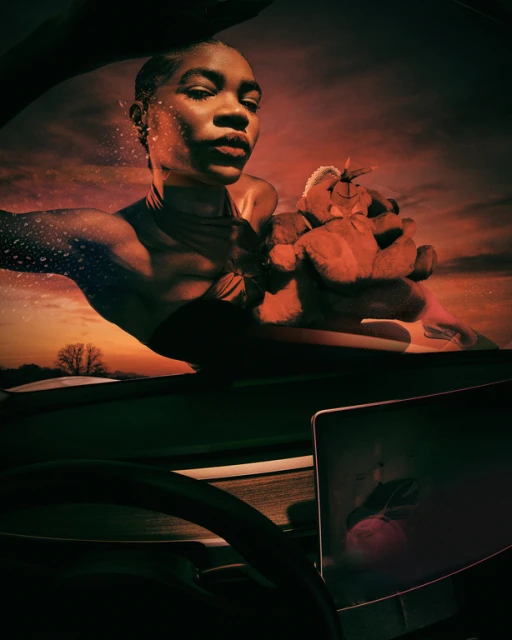 Surreal portrait of Black female adult with teddy bear in vehicle. Sunset background with road and tree. Moody, artistic style.