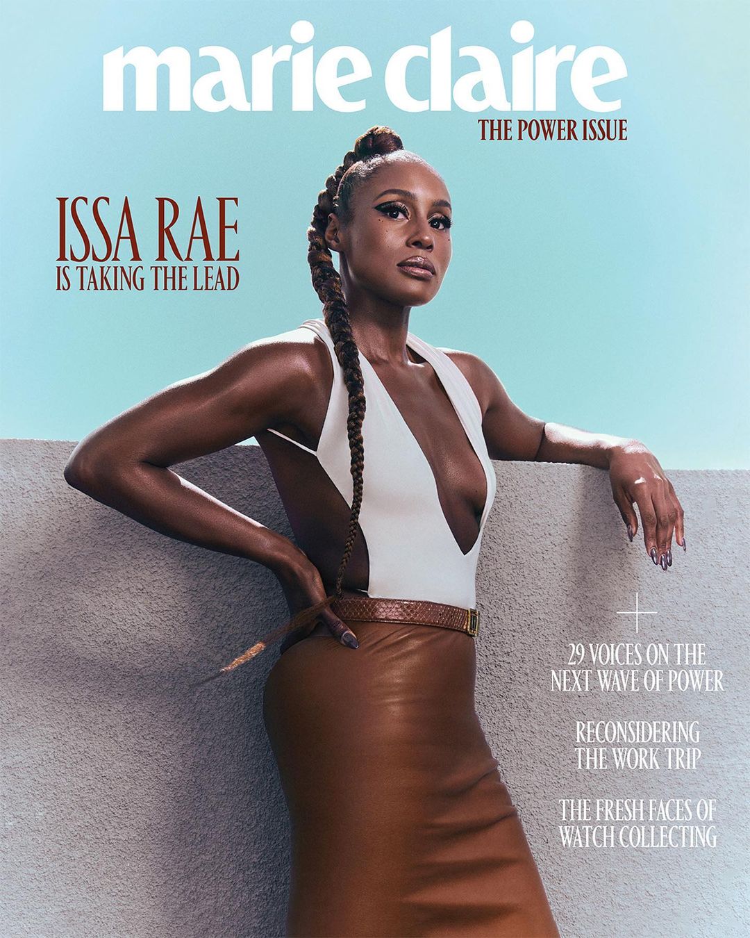 Issa Rae graces the cover of Marie Claire's Power Issue, posing outdoors in a white top and brown leather skirt against a light blue sky.