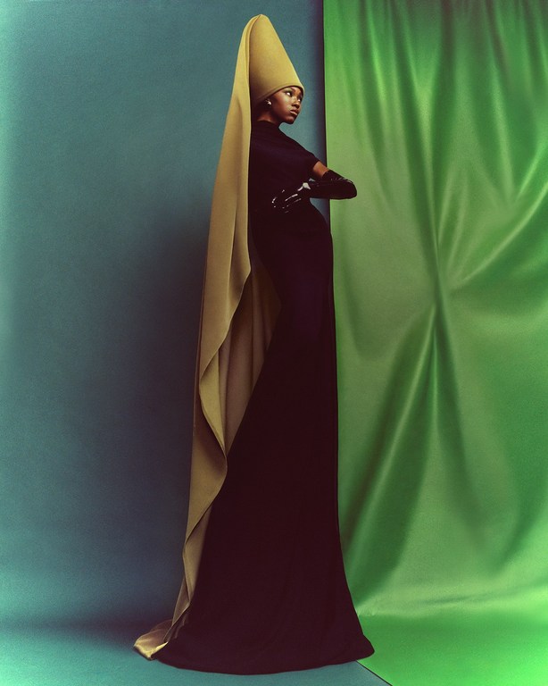Model in long black dress and tall conical hat with drape, photographed by Chrisean Rose