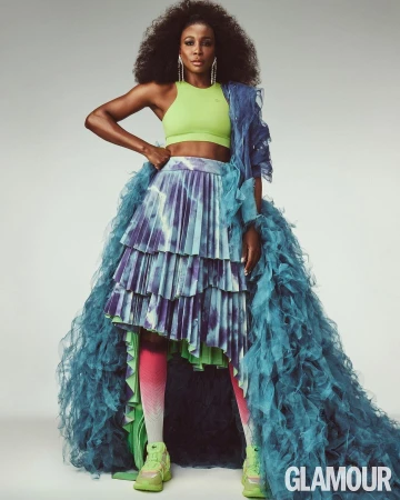 Black woman in a lime green crop top and ruffled blue skirt posing against a light background