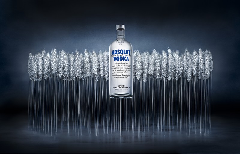 Absolut Vodka bottle showcased with wheat stalks against a dark background, creating a crisp and clean visual composition for advertising.