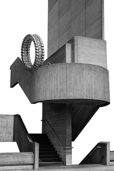 Monochrome architectural shot of a concrete building with multiple levels, staircases, and a circular decorative ring sculpture.