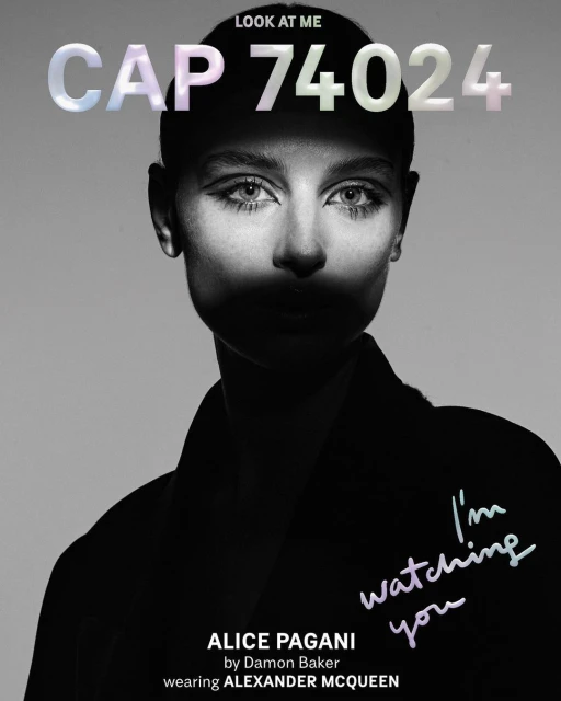 Monochrome portrait of a woman with stylized makeup and short hair, wearing a dark garment with text overlay, 'I'm watching you'.