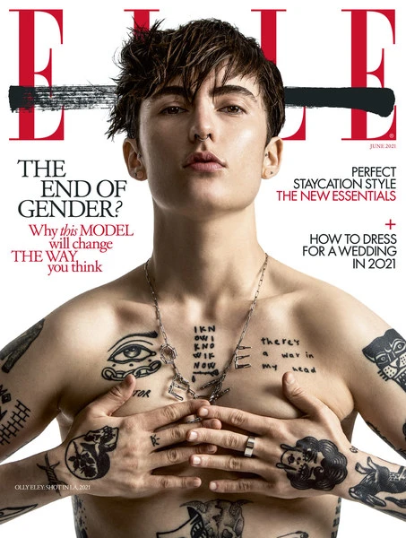 Magazine cover of Elle featuring a person with short hair and tattoos, wearing a silver necklace and ring, holding hands over their chest.