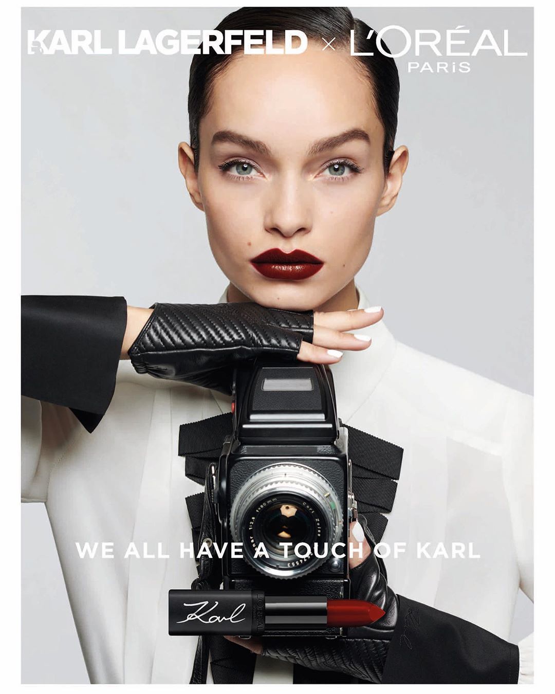Beauty portrait featuring a woman holding a vintage camera and lipstick; Karl Lagerfeld x L'Oreal Paris collaboration; makeup, gloves, fashion.