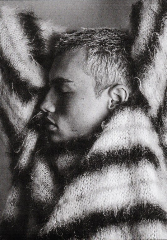 Close-up profile portrait of a young man with short hair wearing a fluffy striped sweater by Damon Baker.
