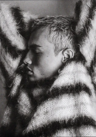 Close-up profile portrait of a young man with short hair wearing a fluffy striped sweater by Damon Baker.
