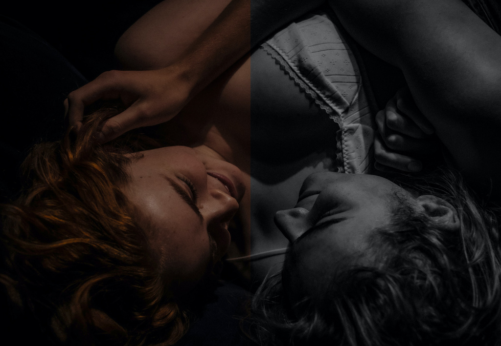 Close-up of a couple lying closely together with intimate expression in low-key lighting by photographer Damon Baker