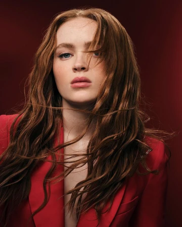 Close-up studio portrait of a young adult female with red hair wearing a red jacket against a red background, beauty and fashion.