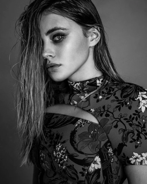 Monochrome portrait of a stylish adult woman with floral-patterned top; eye-level view with wet hair, fair skin, and a neutral expression.