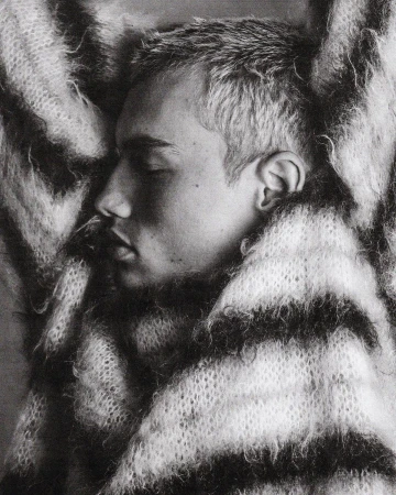 Close-up monochrome profile portrait of a young man wrapped in a thick, textured striped knit scarf by Damon Baker.