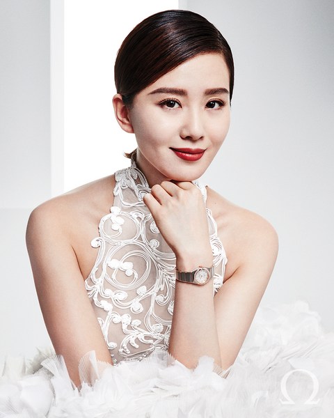 Elegant Asian woman in formal white gown with floral lace and wristwatch. Studio portrait of a fashion model with subtle makeup and hair.