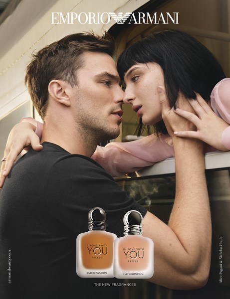 Emporio Armani fragrance ad with a close-up of a couple embracing, set against a commercial vehicle, with two cologne bottles below.