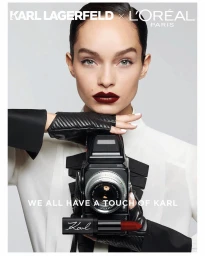 Model wearing black leather gloves holding a vintage camera and lipstick tube against a white seamless background