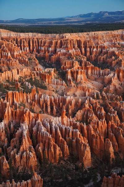 Bryce Canyon National Park aerial view featuring striking red rock formations, trees, and a clear blue sky offering a captivating landscape.