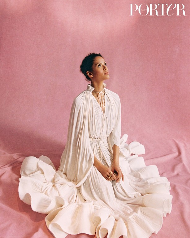Woman in elegant white dress sitting on pink fabric looking up, studio shot, fashion editorial, Porter magazine cover, beauty.