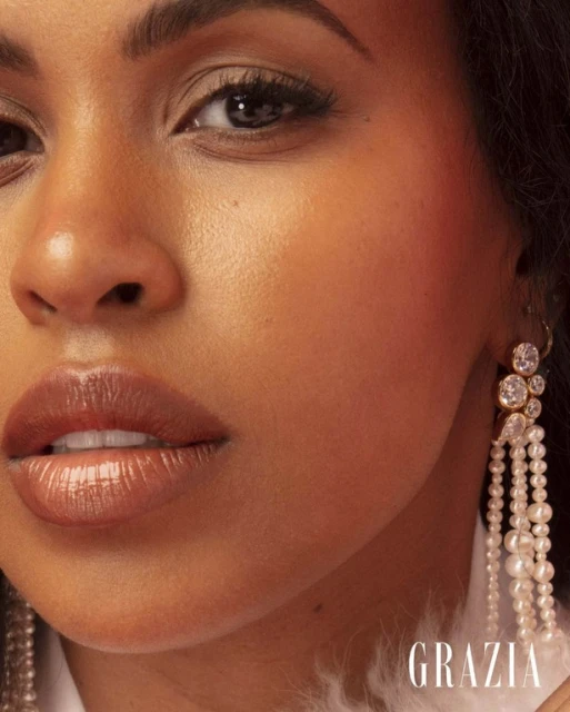 Close-up portrait of a radiant woman with glowing skin and pearl earrings, highlighting beauty and elegance.
