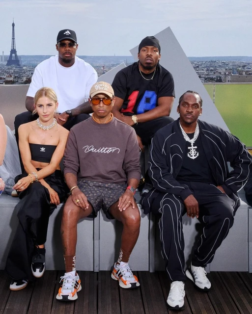 Group portrait of five people with the Eiffel Tower in the background; seated outdoors with urban skyline; stylish fashion.