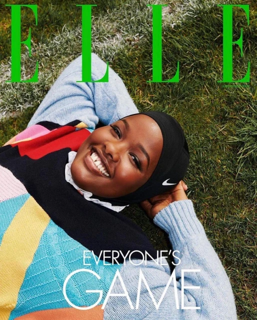 Magazine cover featuring a smiling Black woman in a colorful sweater and Nike headscarf, lying on grass with the bright green ELLE masthead.