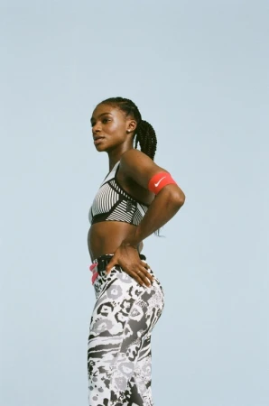 Athletic woman in fitness wear poses in a medium shot against a plain blue background, showcasing sport style and healthy lifestyle.
