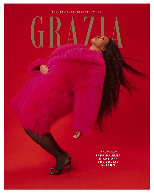 Sabrina Elba poses on a red backdrop wearing a pink faux-fur coat, black hosiery and heels for a GRAZIA special subscribers' cover.